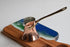 Copper Turkish coffee pot on a wooden stand with a scenic design