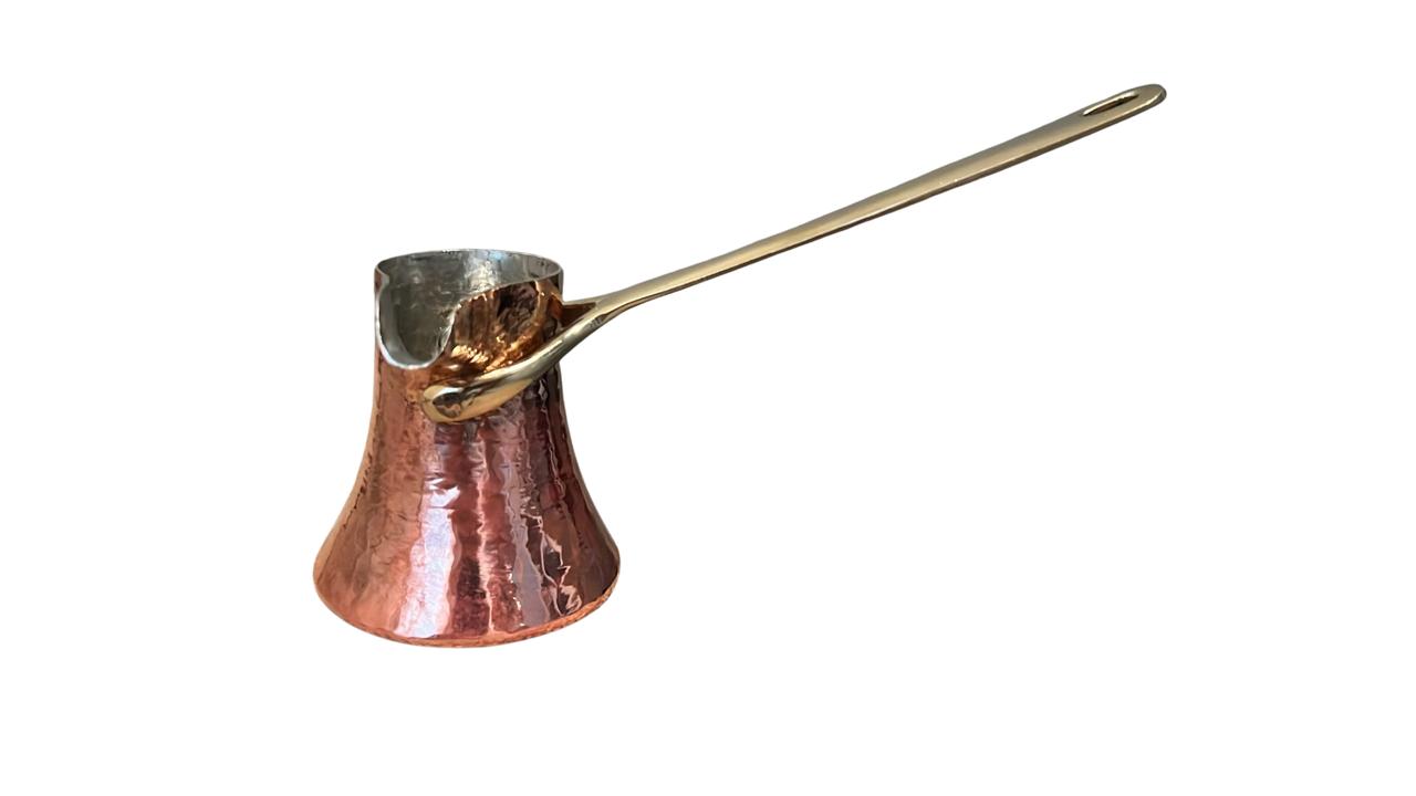 Copper cezve with a long handle on a white background